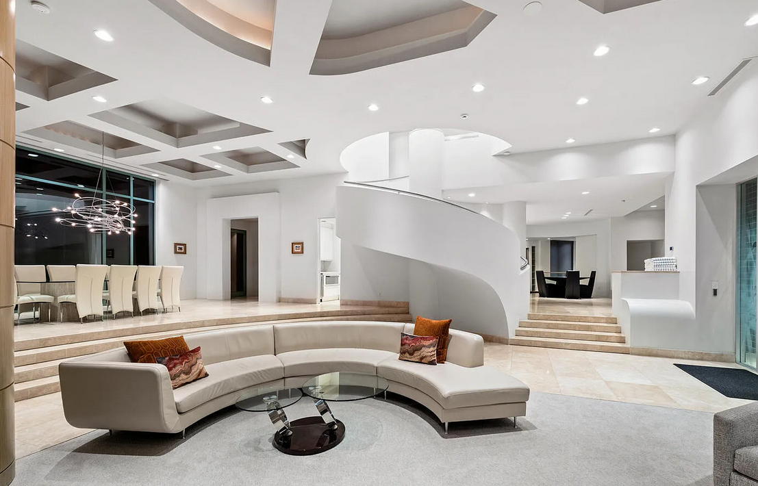 Grand luxury living room with spiral staircase and curved sofa